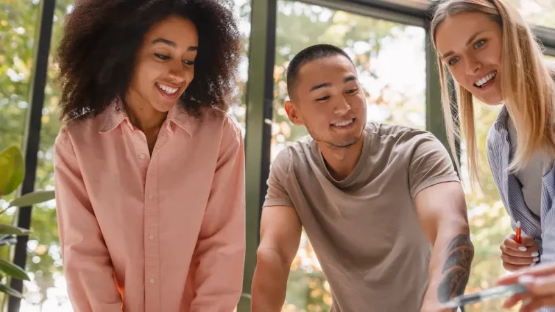 Trois collègues souriants qui collaborent autour d’un projet, illustrant l’esprit d’équipe et la solidarité du profil Loyal, Ennéagramme Type 6.